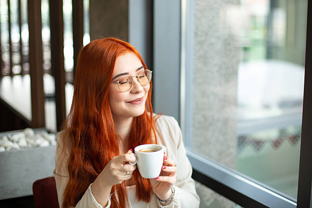 Redhead woman enjoying a cup of coffee by the window in a cafe