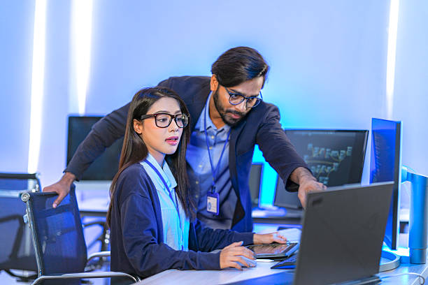 istock Asian female AI programmer and Indian male data analyst reviewing code on a monitor. Diverse tech professionals collaborating on an artificial intelligence project in a modern office. 2225286730