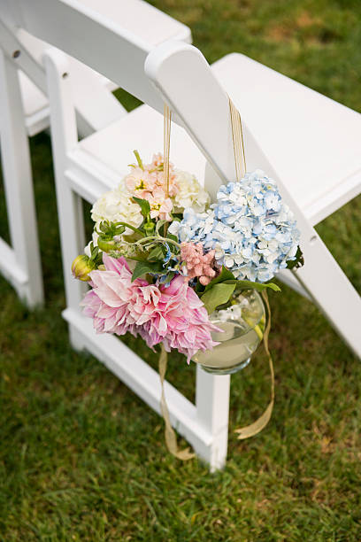 istock Pastel Ceremony Flowers Hanging on White Wedding Chair 2225291383