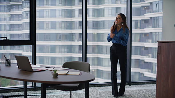 istock Smiling executive calling smartphone sit down at laptop workplace office. 2225298506