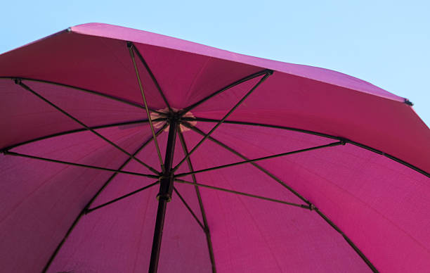 istock A pink umbrella with a blue sky in the background 2225310206