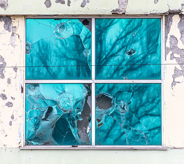 A window with bullet holes in it. The window is blue and has a lot of damage. The window is on a building that is old and has a lot of damage