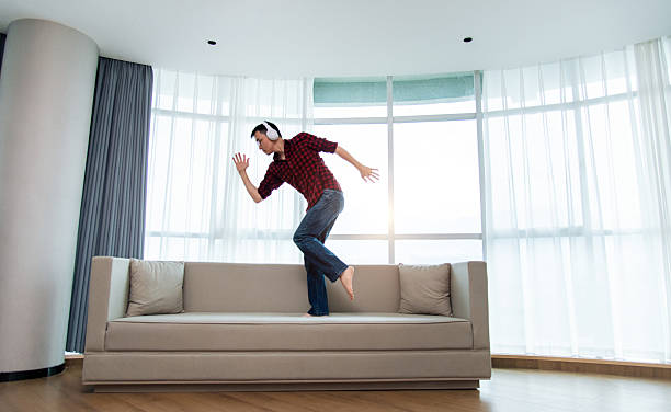 istock Man dancing on the sofa with wearing headphones 2225310910