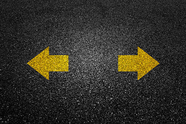 istock Two direction arrow signs on black asphalt road 2225310963