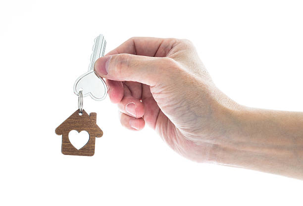 istock Woman hand holding house key on white background 2225311033