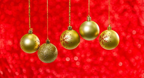 Golden Christmas balls hanging on red shiny background