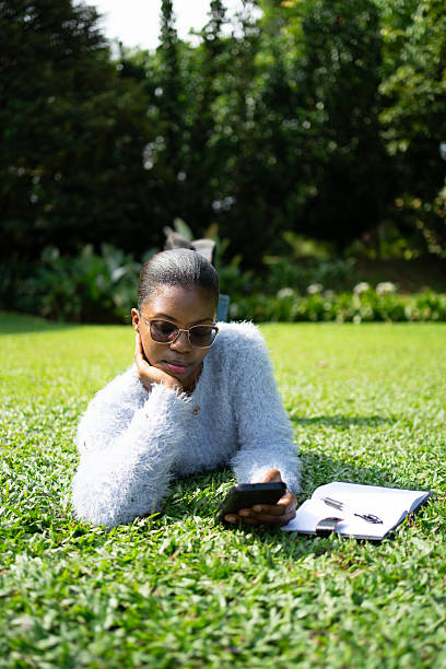 istock Young woman lying on grass using smartphone in park 2225312042