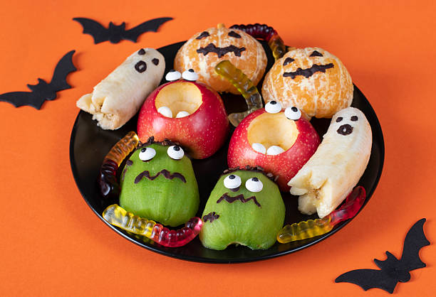 istock Fruit monsters and ghosts for Halloween party on orange background 2225316212