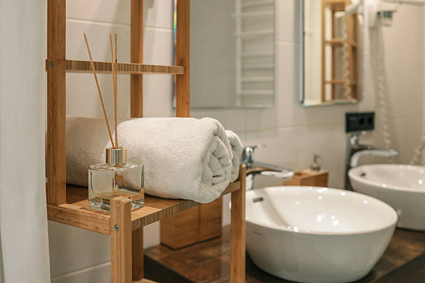 istock Rolled white towel and reed diffuser on a wooden shelf in a modern bathroom with double sinks and minimalist decor, creating a fresh and relaxing spa-like atmosphere 2225317926