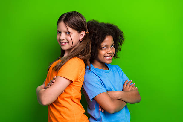 istock Smiling classmates with crossed arms standing against a green background representing happiness 2225317966
