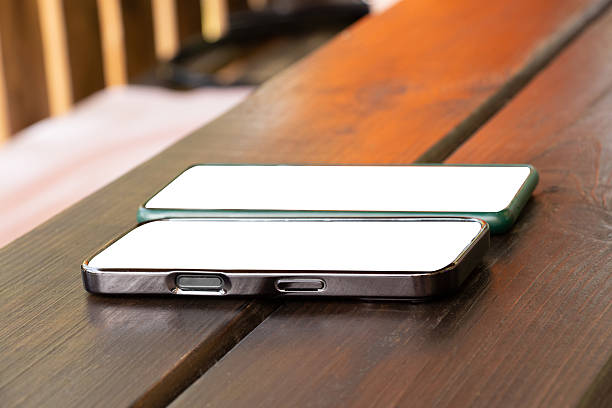 istock Smartphones with white screens on a wooden table as mockups, templates for design, empty screen, place for an application 2225318334