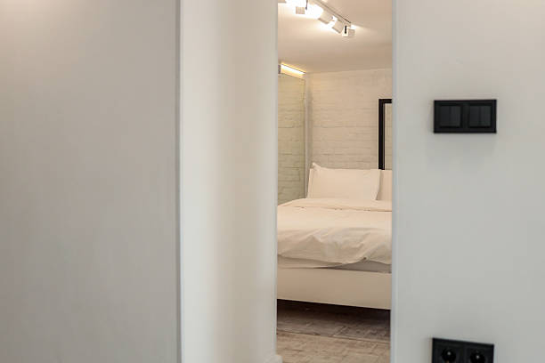 istock Minimalist bedroom interior with white bed and white brick wall, seen through a modern doorway. Bright lighting and clean design create a serene, cozy atmosphere 2225318977