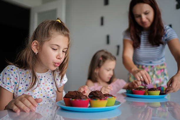 istock Happy family baking and decorating colorful cupcakes together 2225319549