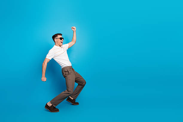 istock Young stylish man posing joyfully against a blue background, expressing casual elegance and vibrant energy 2225321078