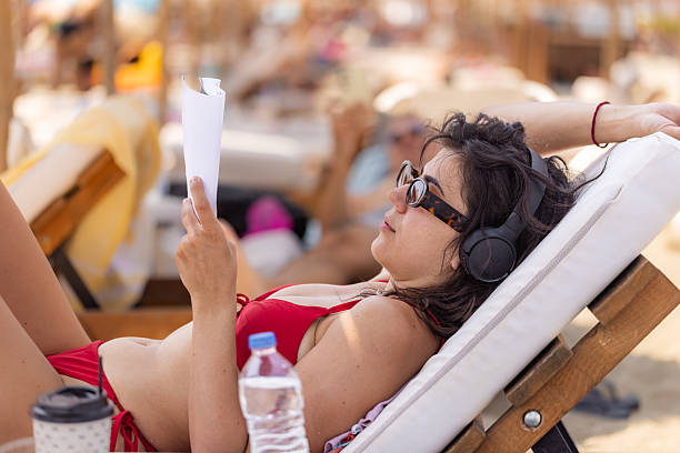 istock Woman in red bikini reading book 2225330764
