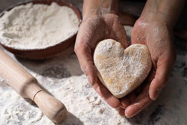 istock Baking concept. Caucasian female hands holding heart shaped dough. 2225331700
