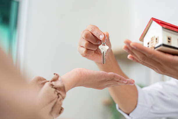 istock Real Estate Closing. Client receiving keys and house model from agent. 2225332509