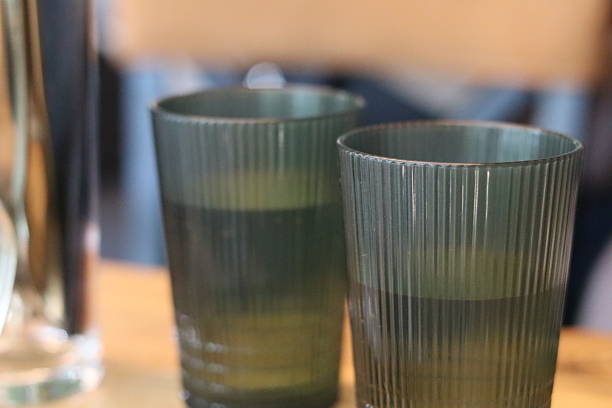 istock Glasses on a wooden table with softly colored water amidst a casual indoor setting 2225334852