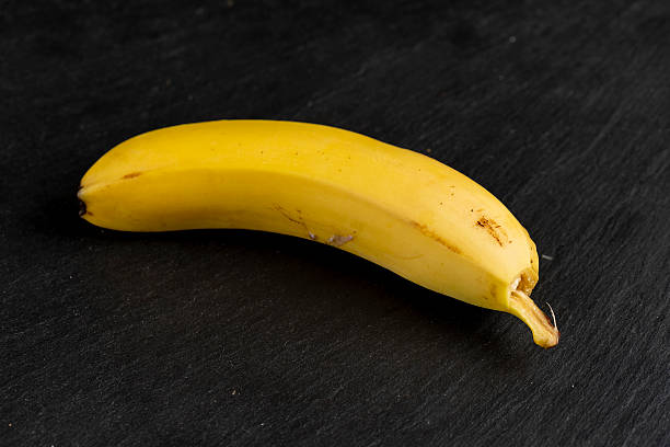 ripe yellow banana on a black slate board, one ripe and sweet yellow banana on a kitchen board made of black stone