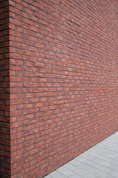 istock Red brick building corner with gray mortar and a neutral paved walkway Clean architectural design 2225338725