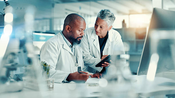 istock Analysis, scientists and team with tablet, lab or discussion for medical research for collaboration. Healthcare, science and mature people with tech for biotechnology, breakthrough and communication 2225338959