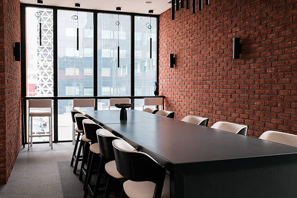 istock Conference room with a long black table surrounded by chairs brick wall and city view from a large window 2225339803