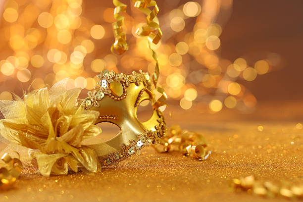 Beautiful carnival mask on golden shiny surface, closeup. Space for text