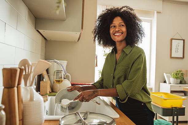A young cheerful woman washing dishes