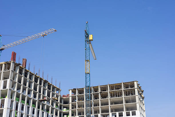 istock Busy construction site features cranes working on a high-rise building, with blue skies providing a perfect backdrop 2225346441