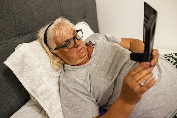 istock Older woman lying in bed, using smartphone 2225346499