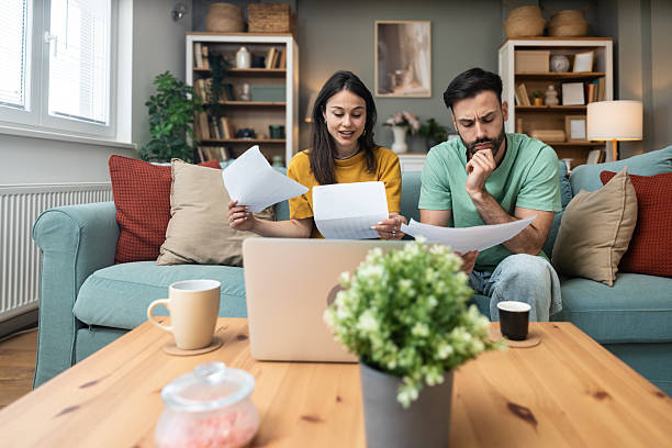 istock Worried young couple sitting on sofa at home, analyzing financial documents and statistics on laptop and paper, stressed about unexpected expenses, debt, or negative budget report results. 2225348447