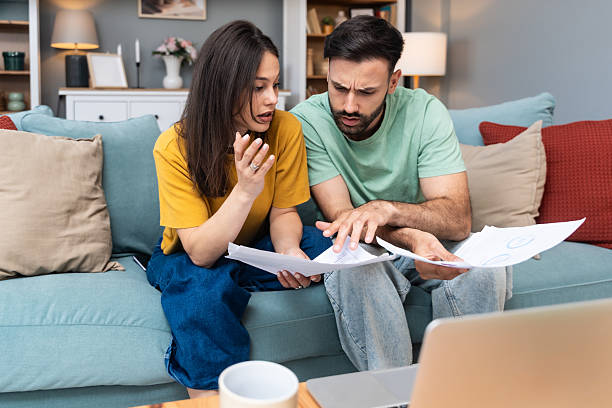 istock Worried young couple sitting on sofa at home, analyzing financial documents and statistics on laptop and paper, stressed about unexpected expenses, debt, or negative budget report results. 2225348457