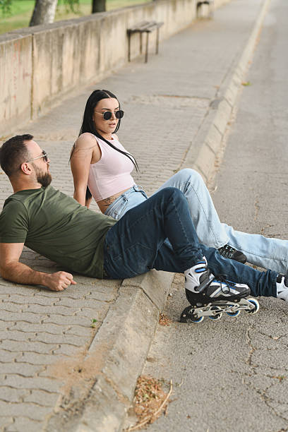 istock Energetic Couple Taking Rest on Pavement Talking and Smiling With Skates Still On 2225351419