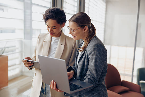 istock Group of female managers standing in modern office while working on laptop and digital tablet 2225353268