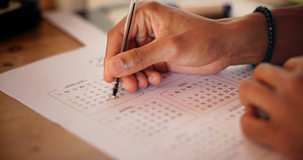 istock Person, schedule and hands writing on calendar for reminder, deadline update and time management. Goals, objective and closeup of planning for tasks, appointment date and notes planner for agenda 2225353812