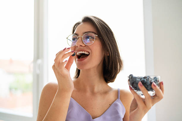 istock Woman enjoying fresh blueberries while smiling in bright kitchen 2225353837