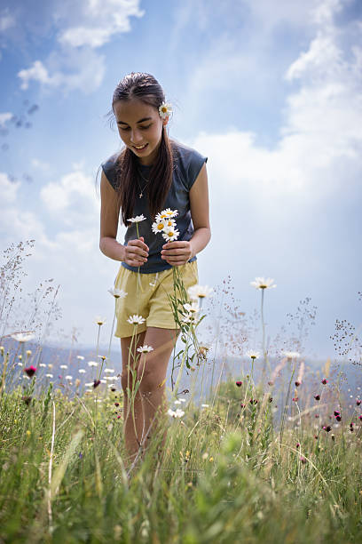 Girl collecting daisies in a field full of wildflowers on a sunny summer day, enjoying nature and freedom