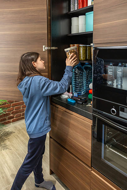 istock Young female preparing 72 hours emergency survival kit stored in a kitchen cupboard. 2225357884