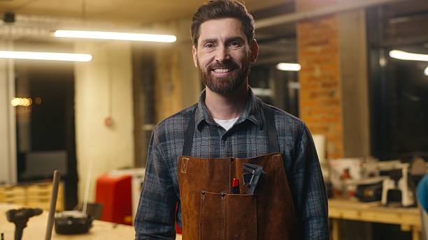 istock Joyful happy Caucasian worker man builder guy carpenter male looking at camera portrait indoors small business owner smiling in workshop carpentry designer work job wood master in uniform woodworking 2225362988