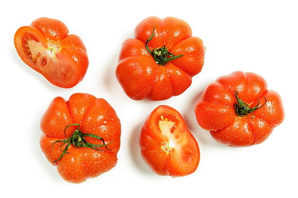 Fresh vibrant tomatoes, including whole and sliced halves, showcased with water droplets on a clean white background. Their vibrant red color, glossy texture, and visible seeds highlight their freshness and natural appeal. Perfect for food, nutrition, and healthy eating concepts.