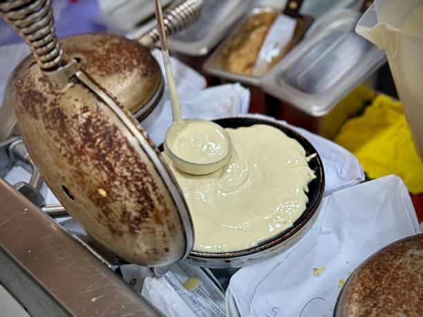 istock Waffle seller scooping waffle pancake raw mix onto toaster 2225363333