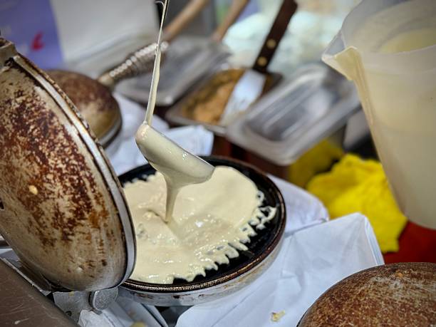 Waffle seller scooping waffle pancake raw mix onto toaster