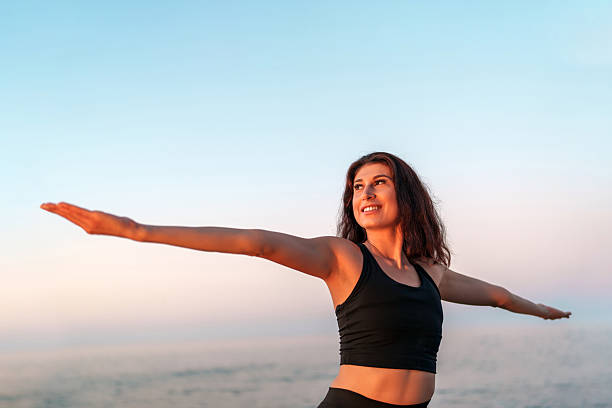 istock Young woman practicing yoga on the beach at sunset 2225364167
