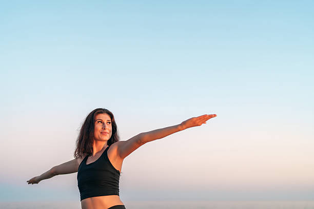 istock Young woman practicing yoga at sunset with open arms and serene expression 2225364186