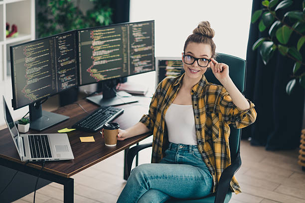 istock Young female programmer working remotely in a modern home office with multiple monitors and a stylish casual outfit 2225367493