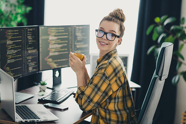 istock Young woman programmer working remotely in casual home office with multiple screens displaying code 2225367920