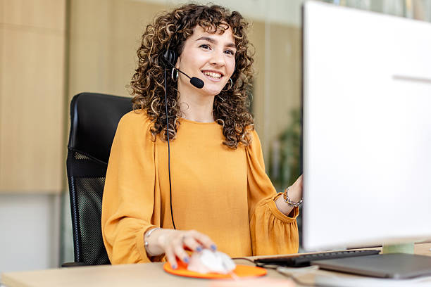 istock Professional woman working in a modern office using headset and computer during a business meeting with colleagues 2225371438