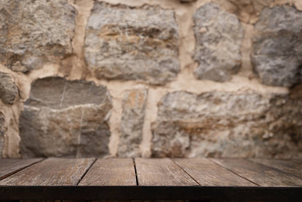 istock Wooden table mock up with stone wall background. Empty wooden table copy space close up surface template place for product placement and advertisement soft cozy background 2225373497