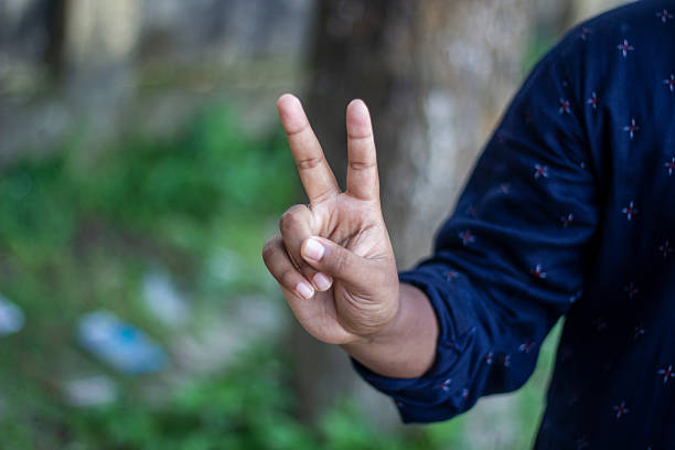 istock A man pointing two fingers of his hand forward and green background 2225379471