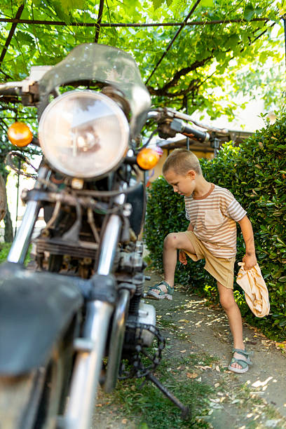 istock Little boy helping with motorcycle maintenance. Dirty hands and focused expression while doing a task. 2225379938
